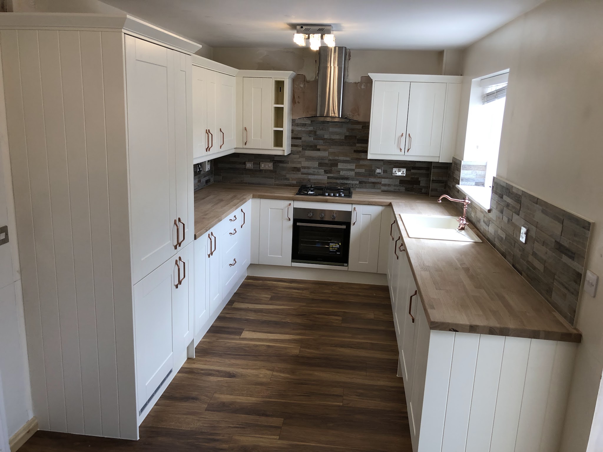 A fitted kitchen with panelled units and a wood-effect floor