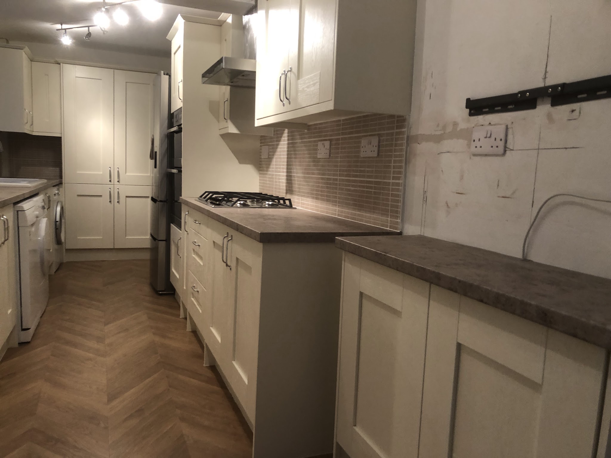 A kitchen with a herringbone floor being fitted